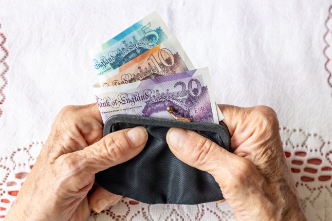 Worked hands of senior woman holding old fashioned ladies purse with British pounds. Economic concept, Financial situation of seniors in UK. Flat lay, close-up