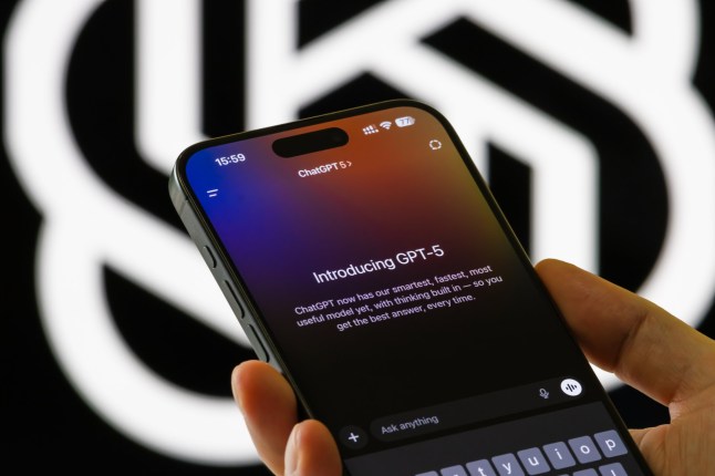 CHONGQING, CHINA - AUGUST 9: In this photo illustration, a person holds a smartphone showing the Introducing GPT-5 interface in the ChatGPT app, with text describing the model's capabilities, in front of a blurred OpenAI logo on August 9, 2025 in Chongqing, China. (Photo illustration by Cheng Xin/Getty Images)