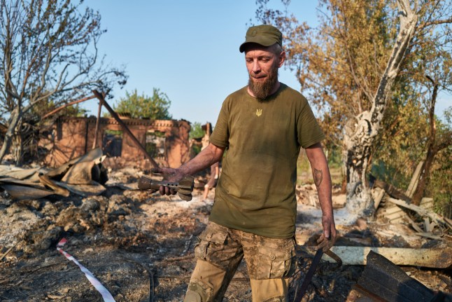 SLOVIANSK, UKRAINE - AUGUST 20: A Ukrainian soldier holds the remains of a shell at the site of a Russian Shahed drone strike that destroyed vehicles and residential buildings the previous day on August 20, 2025 in Sloviansk, Ukraine. Sloviansk is the city where the war in Donbas began in 2014, marked by its occupation by Russian militias led by Igor Strelkov, also known as Girkin. The town is located in Donetsk Oblast, a Ukrainian region cited in peace-talk discussions involving U.S. President Donald Trump and Russian President Vladimir Putin over a potential frontline freeze and territorial exchanges. (Photo by Pierre Crom/Getty Images)