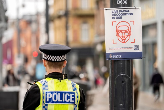 A police officer near a 'Live facial recognition in use' sign as a Live Facial Recognition (LFR) van is deployed on Briggate in Leeds, as West Yorkshire Police use the facial recognition technology for the first time in Yorkshire. Picture date: Tuesday November 11, 2025. PA Photo. LFR will be used in authorised locations across the county to help identify individuals who are wanted by the courts, subject to arrest, or pose a risk to the public. It will also be used to locate missing persons, key witnesses to serious offences and victims of offences such as modern slavery. The technology works by scanning faces in real time and comparing them against an authorised watchlist of individuals of interest to the police. Photo credit should read: Danny Lawson/PA Wire