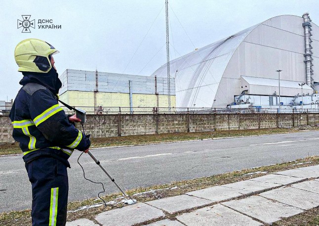 (FILES) This handout photograph taken and released by Ukrainian Emergency Service on February 14, 2025 shows an employee working outside the New Safe Confinement (NSC), which protects the remains of reactor 4 of the former Chernobyl Nuclear Power Plant following a drone attack on its cover built to contain radiation. The International Atomic Energy Agency (IAEA) announced on December 7, 2025 that its teams had been in Ukraine since early December to assess nuclear safety and had found that the Chernobyl arch had lost its "primary safety functions" following bombing in February 2025. (Photo by Handout / UKRAINIAN EMERGENCY SERVICE / AFP via Getty Images) / RESTRICTED TO EDITORIAL USE - MANDATORY CREDIT "AFP PHOTO / UKRAINIAN EMERGENCY SERVICE " - NO MARKETING NO ADVERTISING CAMPAIGNS - DISTRIBUTED AS A SERVICE TO CLIENTS