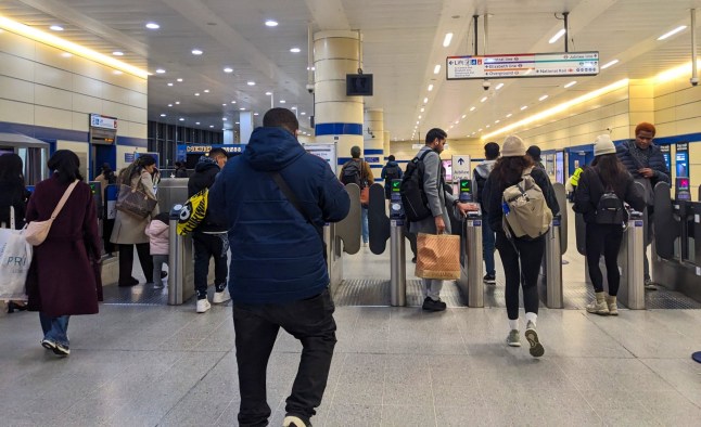 Commuters and travelers passing through the automatic ticket gates at Stratford Station, a vital public transport interchange for the Tube and rail