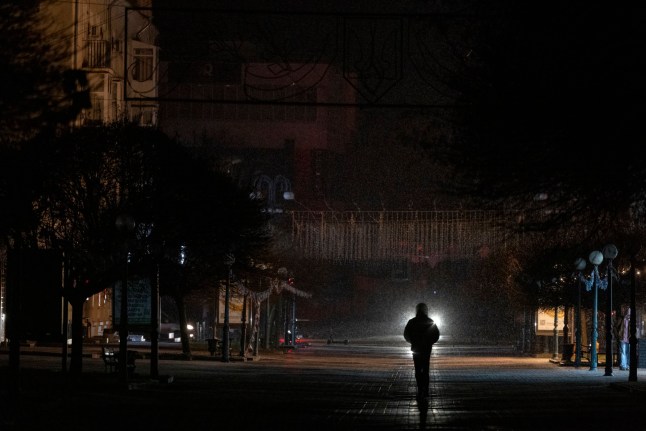 SUMY, UKRAINE - DECEMBER 9: People walk through the streets of Sumy during emergency power cuts on December 9, 2025 in Sumy, Ukraine. The city faces near-daily power outages as repeated Russian drone strikes continue to damage critical infrastructure. Water supply, heating systems, and essential services are operating on backup power, leaving residents to cope by candlelight while repair crews work under the persistent threat of renewed attacks. Energy workers operate in hazardous conditions to restore electricity as rolling blackout schedules remain in effect across the wider region. (Photo by Maksym Kishka/Frontliner/Getty Images)