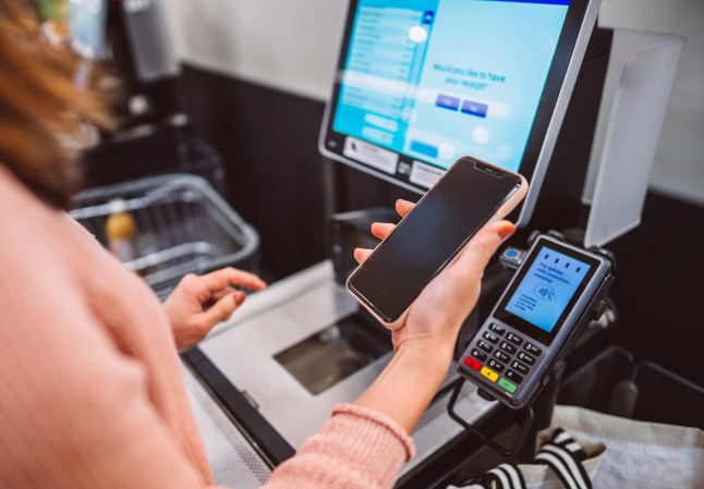 Customer paying with smart phone using contactless payment at self checkout