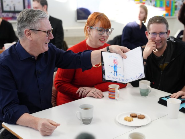Prime Minister Sir Keir Starmer looks at a drawing of himself as he meets local residents during a visit to the Emmer Green Youth & Community Centre in Reading, Berkshire, to mark the beginning of the new year and highlight the government's decision to freeze rail-fares. Picture date: Monday January 5, 2026. PA Photo. Photo credit should read: Jonathan Brady/PA Wire