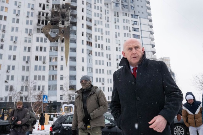 Defence Secretary John Healey meets emergency service workers at the scene of last night's drone attack which hit a residential area in the east of Kyiv, killing one person.